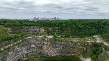 Fototapeta na wymiar Abandoned quarry at mining operation with Richmond, VA city skyline on landscape horizon under partly cloudy sky