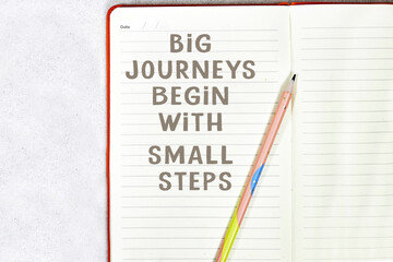 Big journeys begin with small steps on notebook with pencil isolated on gray background