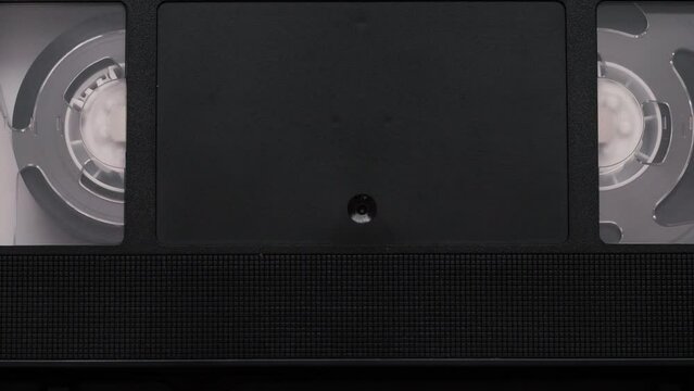 VHS videocassette is put into the video recorder to watch the video, another video cassette is on the video-tape recorder.