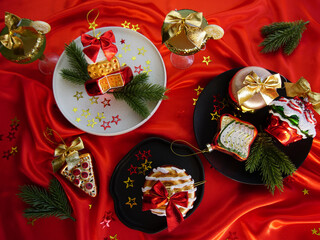 New Year's desserts. Creative table setting with Christmas tree toys. Plates with Christmas toys are placed on a red satin tablecloth.