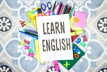 Learn english concept - pencils and notebooks and sticky note and with pins, felt pen on tile...