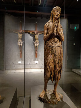 Florence ITALY - August 5, 2023 - Sculpture of the penitent Saint Mary Magdalene by Donatello in the museum dell'Opera del Duomo with Jesus Crucified in the background