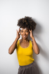Young cheerful black casual woman wearing glasses. Afro hairstyle cheerful model against white wall.