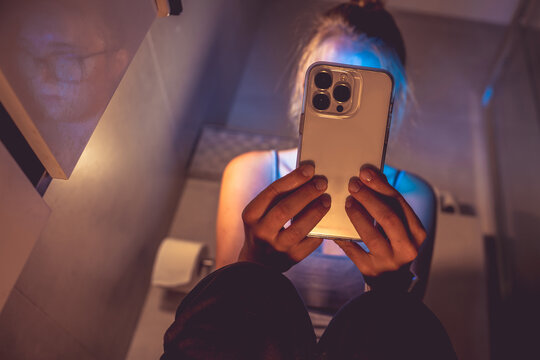 Phone addiction. Woman with phone in the toilet.