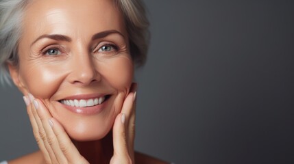 Naklejka premium Beautiful 50 year old woman with clean fresh skin on a light background. Facial care, cosmetology, beauty and spa concept