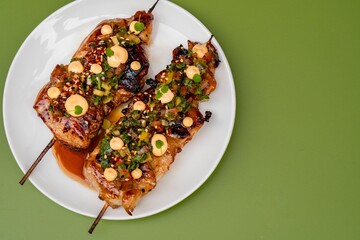 there are two meat skewers on the plate and sauce is in the center