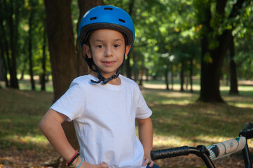 Portrait of a little boy in a safety helmet sitting on a bike in the forest. About six years old.