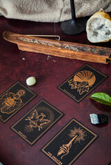 Oracle reading cards on red mat table with candles gemstones plants and encense