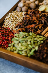 Cinnamon, clove, star anise, cardamom, juniper, nutmeg, ginger and pepper whole spices on a wooden tray