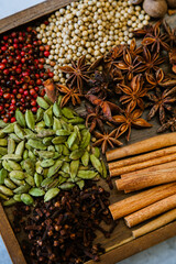 Cinnamon, clove, star anise, cardamom, juniper, nutmeg, ginger and pepper whole spices on a wooden tray