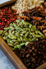 Cinnamon, clove, star anise, cardamom, juniper, nutmeg, ginger and pepper whole spices on a wooden tray