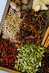Cinnamon, clove, star anise, cardamom, juniper, nutmeg, ginger and pepper whole spices on a wooden tray
