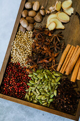 Cinnamon, clove, star anise, cardamom, juniper, nutmeg, ginger and pepper whole spices on a wooden tray