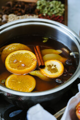 Pot of hot cider wassail with sliced fruits and whole spices for winter dinners