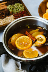 Pot of hot cider wassail with sliced fruits and whole spices for winter dinners