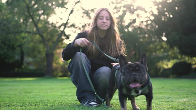 A teenage girl plays with her dog in the park