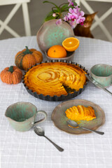 Homemade pumpkin pie with cottage cheese and orange zest and juice served with handmade ceramics - green and pink tea set