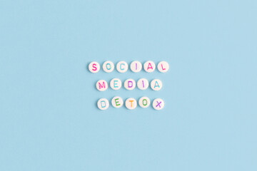 Social media detox. Quote made of white round beads with multicolored letters on a blue background.