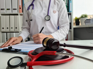 Judge gavel handcuffed doctor dealing with insurance paperwork in medical clinic