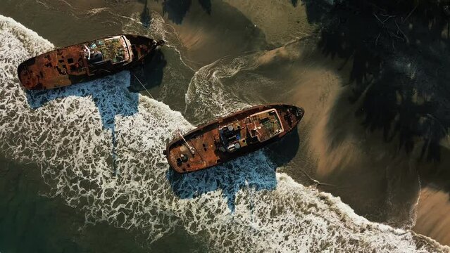 Top-down view of sunken ships covered with rust. Ancient ships that are moored off the coast of the island. Shipwreck in the ocean, the remains of a ship off the coast.