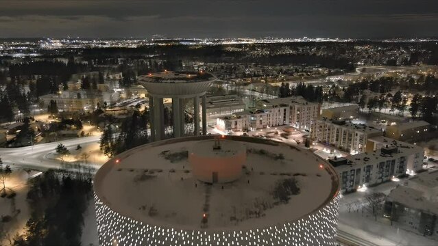 Vantaa.Finland-December 29.2021: Aerial shot of the new water tower next to the old one in Hiekkaharju Vantaa. Awesome cityscape. Nighttime. Wintertime. Drone slowly moving backwards.