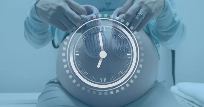Fast moving clock over midsection of pregnant caucasian woman holding bootees beside belly