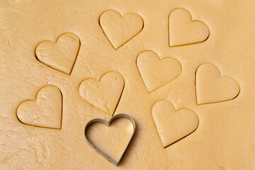 Heart shaped cookie cutters cutting out holiday. Cutting out heart shaped cookies from dough.