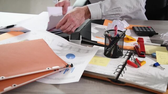 Disorganized businessman working and looking for something on a messy desk