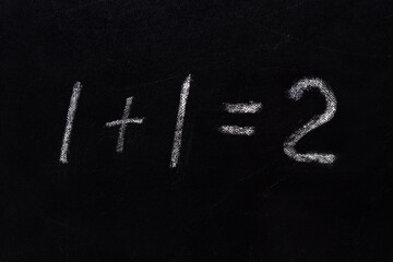 Simple math equation 1 1 2 written school board chalk. Blackboard equations one plus one equals two written black board background. 1 plus 1 equals 2 writing chalkboard background. Elementary school