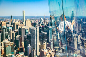 The girl stands facing away on the observation deck of a skyscraper in New York, admiring the view of the city skyline