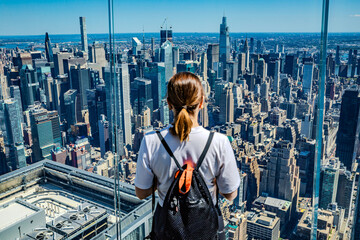 The girl stands facing away on the observation deck of a skyscraper in New York, admiring the view...