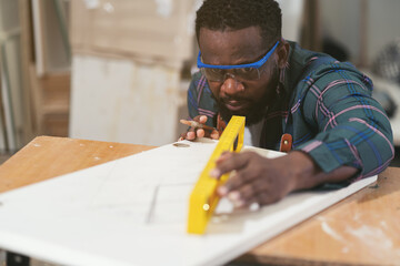 African American male carpenter working at wood factory. Male joiner in wood factory