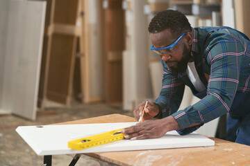 African American male carpenter working at wood factory. Male joiner in wood factory