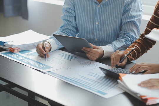 Financial analysts analyze business financial reports on a digital tablet planning investment project during a discussion at a meeting of corporate showing the results of their successful teamwork.