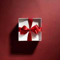 Blank white gift box open or top view of white present box tied with red ribbon bow isolated on dark red background with shadow minimal conceptual