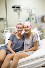 Cancer-stricken friends sitting in hospital bed, positive attitude, smiles. Ai generated.