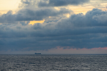 Seascape in the Baltic Sea at sunset.  A cargo ship at sea, the sky is overcast.