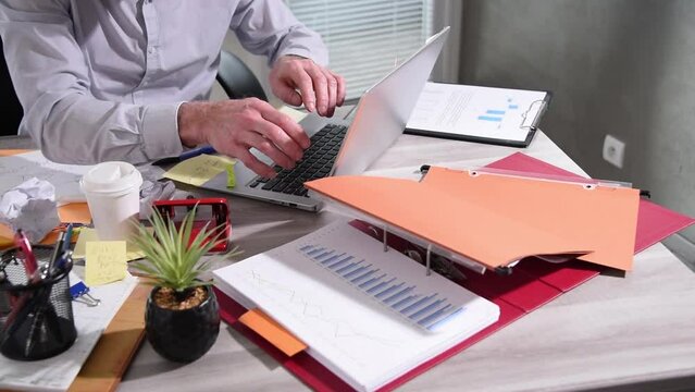 Disorganized businessman working and looking for something on a messy desk