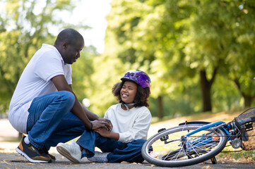 Father helping his kid after falling from the bike