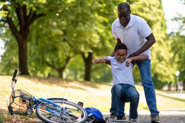 Dad helping his son after falling donw from the bike