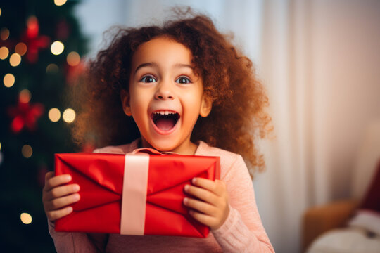 Little girl holding a gift box on the christmas tree background