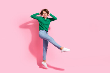 Full body shot of energetic lady dancing hands touching haircut jumping air boogie woogie motion isolated on pink color background