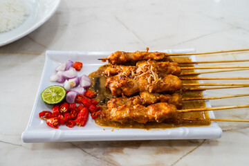 Grilled chicken satay with peanut sauce. served with sliced red chilies, red onions and lemon,