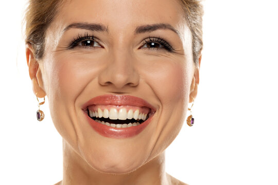 A portrait of a joyful woman with a beautiful smile and tasteful makeup, revealing her naturally white and healthy teeth, expressing happiness and confidence.