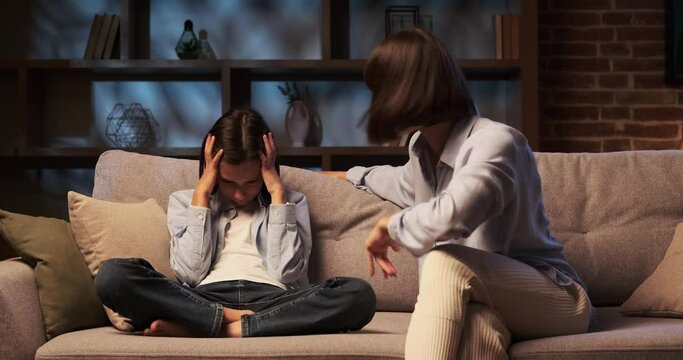 Mother voice fills the air as she shouts at son, who sits on the sofa, face marked by a mixture of fear and defiance. The room seems to shrink under the weight of anger.