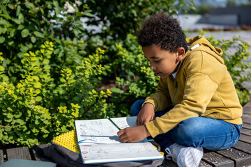 African american schoolboy looking involved while doing hometask