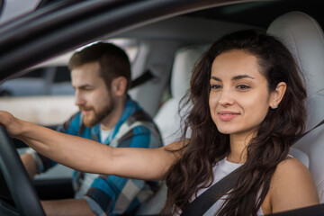 Smiling couple enjoying summer trip. Woman driving a car with his boyfriend on passenger seat. Travel adventure drive, happy summer vacation concept