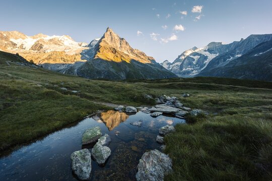 Summer landscape view with the Besso mountain relecting in a stream at sunset