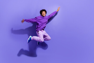 Full length photo of satisfied guy wear purple sportswear pullover flying hold arms like wings...