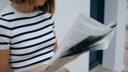 Hands holding morning newspaper closeup. Focused tourist girl reading magazine - obrazy, fototapety, plakaty